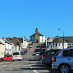 Bowmore village main street on the Isle of Islay Scotland on a sunny day – home of Bowmore Distillery Est. 1779, the oldest distillery on Islay, with the iconic round church at the top of the hill | 蘇格蘭艾雷島波摩村主街 波摩蒸餾廠所在地 1779年創立 圓形教堂
